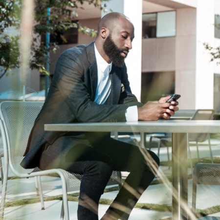 Confident, professional man sitting outside looking at his phone