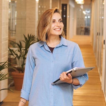 Happy professional woman walking down an office hallway