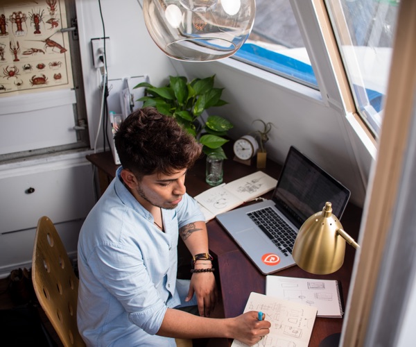 Young man at his desk writing a plan in his notebook