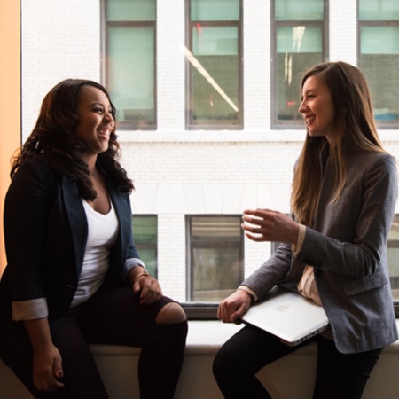 Two young women sitting near the window talking