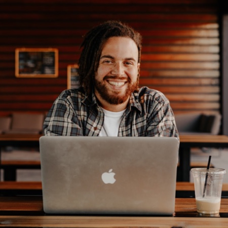 Happy young man looking up from his laptop