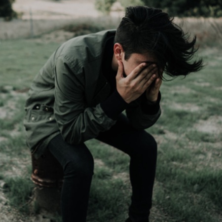 Depressed young man with his head in his hands
